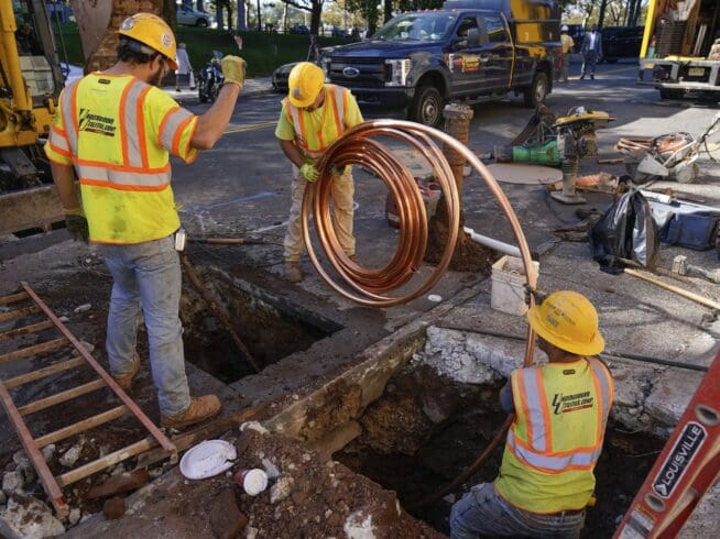 Workmen prepare to replace older water pipes with a new copper one. (AP Photo/Seth Wenig)