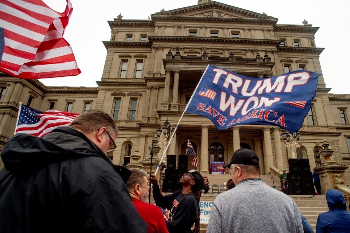 A protester waves a Trump flag during rally at the Michigan Capitol, Oct. 12, 2021, in Lansing, M.I.