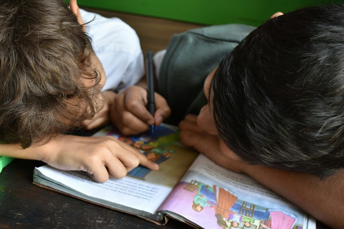 Two children writing in a book.