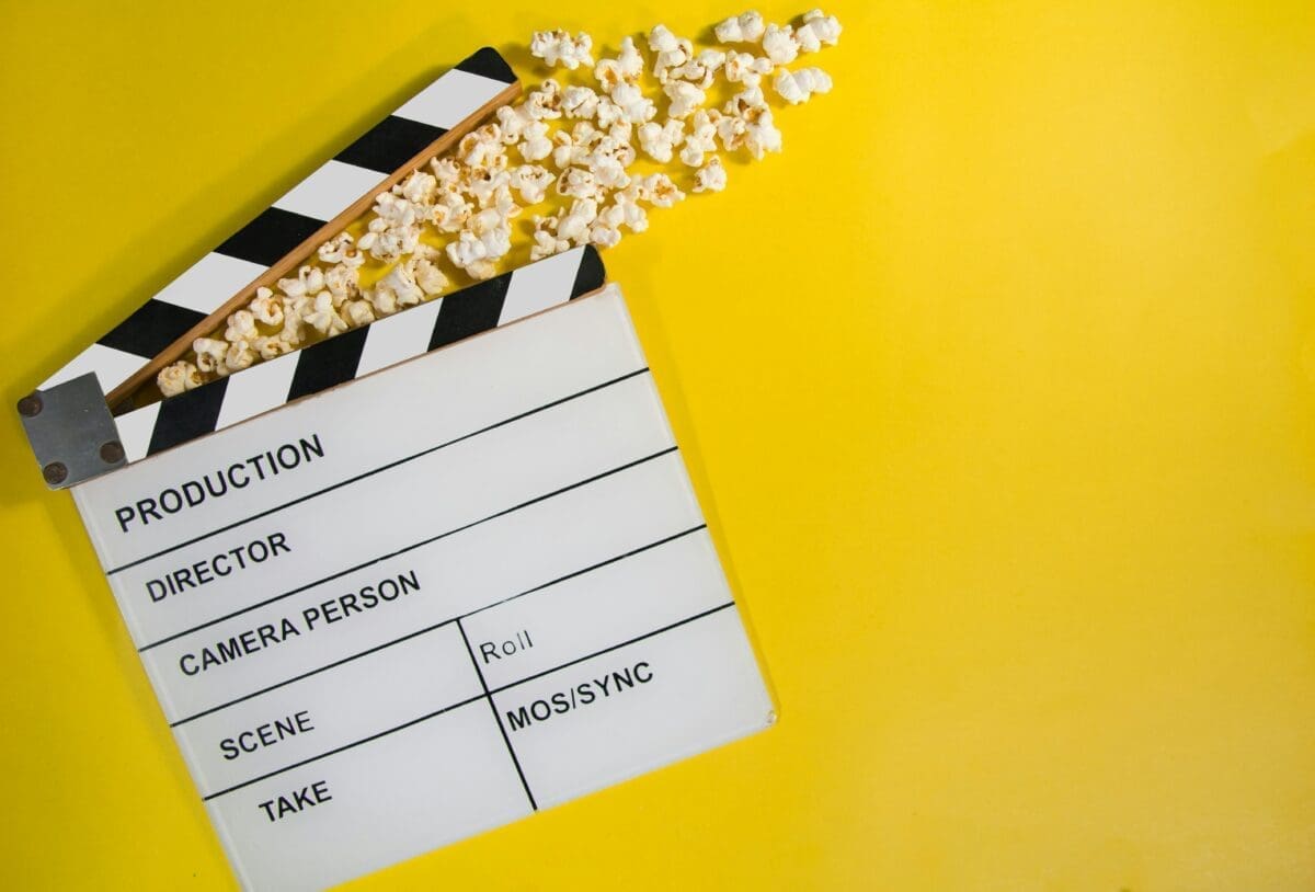 Clapperboard and popcorn on a yellow background.