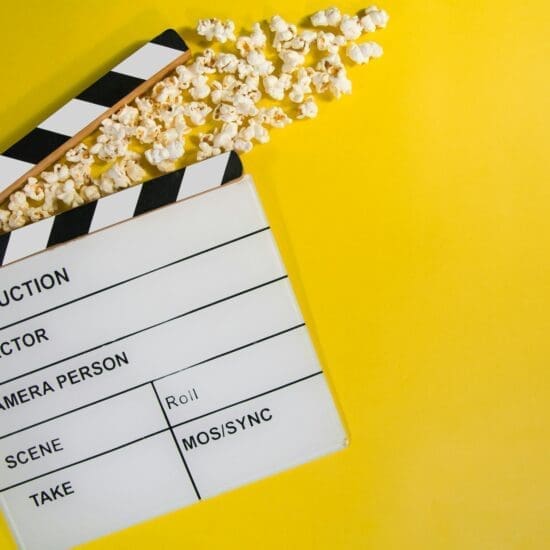 Clapperboard and popcorn on a yellow background.